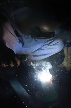 Welder with sparks arcing, industrial background