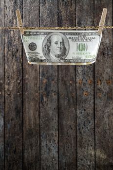 One Hundred Dollars hanging on the clothesline.old wood background.