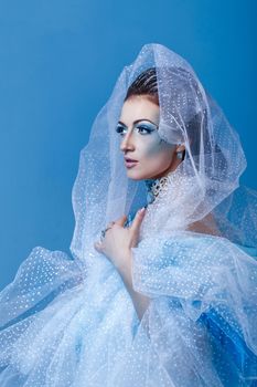 Attractive young girl with a theatrical makeup on the face in the image fabulous snow queen