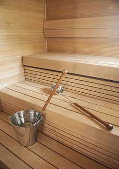 Bucket and scoop in wooden finnish sauna background.