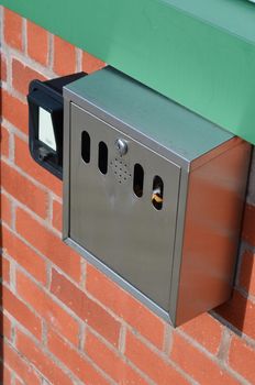 A modern metal cigarette bin outside a public building.
