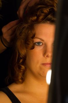 Woman applying make up for a bride in her wedding day near mirror, wamr light from lightbulbs