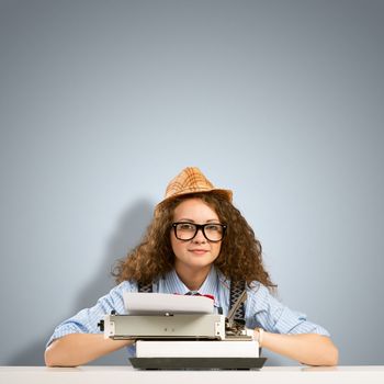 image of a young woman writer at the table with typewriter