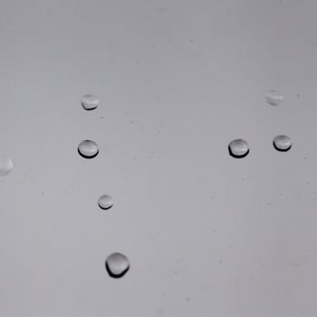 Drops over a glass window, with gray sky behind