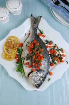 Baked Fish (Dorado) decorated with slices of peppers with capers