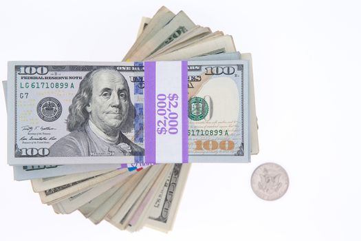 Stacked bundles of American 100 dollar bills in bank wrapping forming a spiral viewed from above isolated on white with a single dollar coin alongside and copyspace