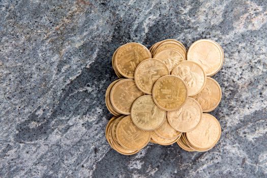 Overhead conceptual financial background image of a pile of neatly stacked dollar coins arranged in a symmetrical pattern on a stone surface with copyspace