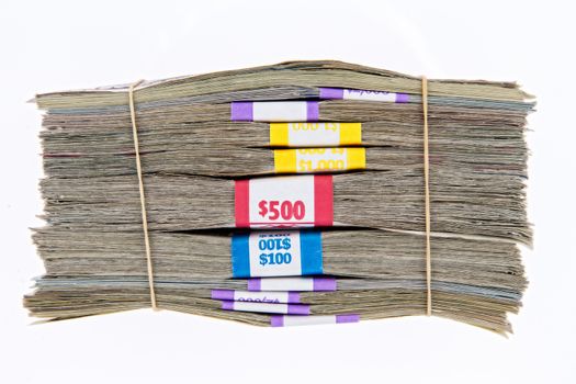 Bank bundles of different denomination dollar bills stacked on top of each other and secured with two rubber bands, side view isolated on white