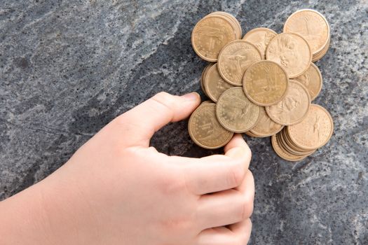 Hand of a man stacking American dollar coins arranging them in a neat symmetrical configuration on a stone countertop conceptual of saving, financial planning and budgeting, overhead view