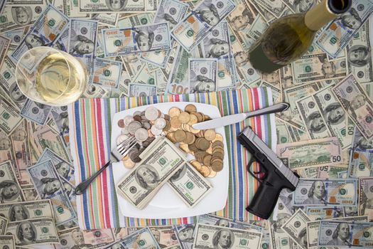 Overhead view of a place setting with a plate of money, a handgun and champagne on 100 dollar bills depicting wealth through crime and racketeering or celebrating a win and keeping it secure