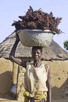 portrait of a woman in her village carrying a load on the head
