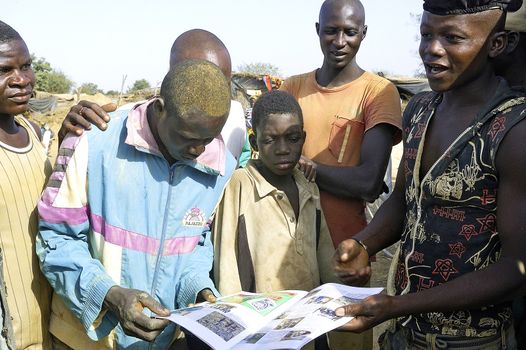 Gold miners look with surprise a review with a report on them made by a French photographer and gold prospector in Burkina Faso