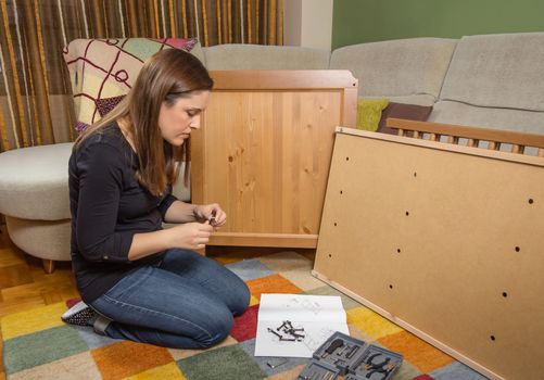 Girl with tools reading the instructions to assemble a new furniture for home
