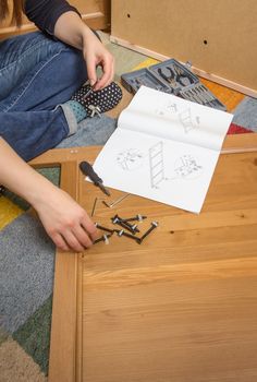 Closeup of girl with tools and instructions ready to assemble a new furniture for home