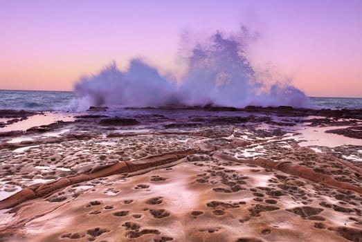 Splashing waves against rocks at the South Avoca ledge at sundown