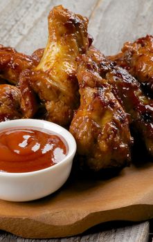 Chicken Legs and Wings Barbecue with Ketchup on Wooden Plate closeup