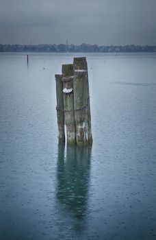 Poles in the middle of a lake under the rain