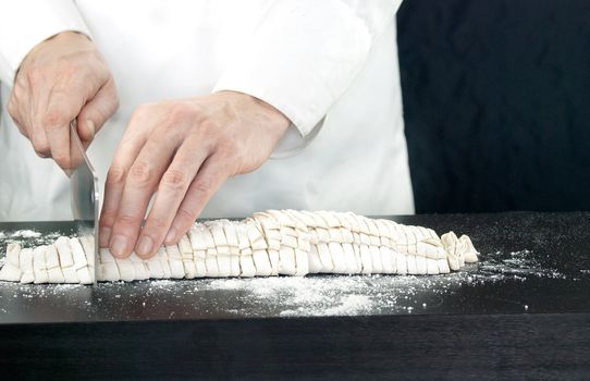 Close-up of a Chef cutting fresh pasta, left side view.