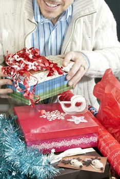 Close-up of a smiling man surrounded by the accoutrement of christmas present wrapping.