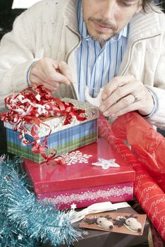 Close-up of a man concentrating on wrapping christmas gifts.