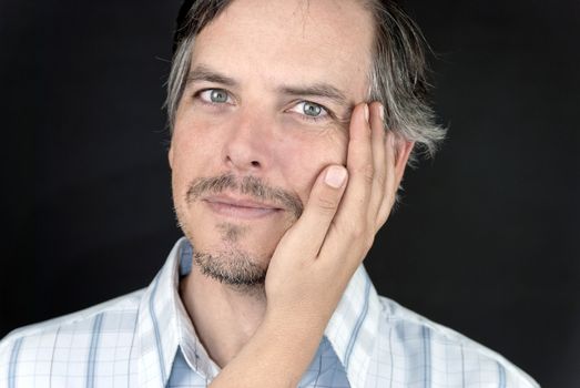 Close-up of a serene man with a woman's hand on his cheek