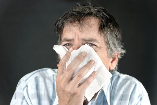 Close-up of a man sneezing into a tissue.