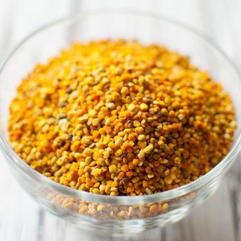 raw organic bee pollen over wooden board