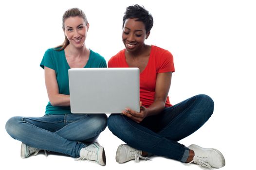 Smiling two friends watching videos on laptop