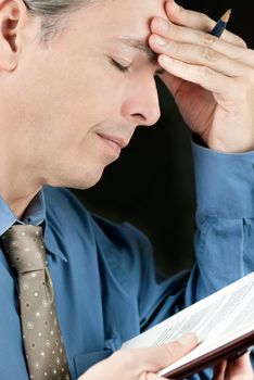 Close-up of a stressed businessman rubbing his forehead.