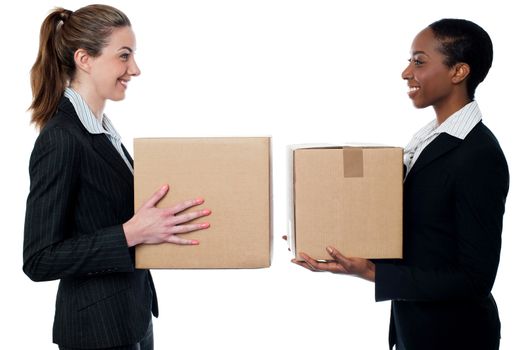 Smiling female executives holding cardboard boxes