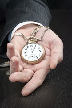 Close-up of a businessman displaying an open pocket-watch in his hand.