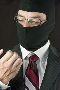 Close-up of a businessman wearing a balaclava checking his nails