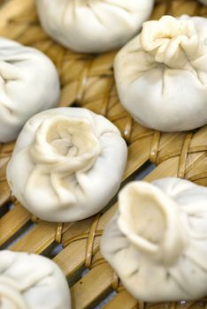 Close-up of a bamboo steamer filled with Tibetan style meatball and vegetarian momos ready to be steamed.