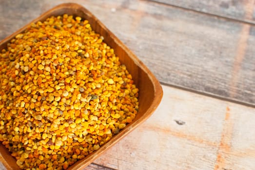 raw organic bee pollen over wooden board