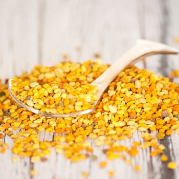 raw organic bee pollen over wooden board