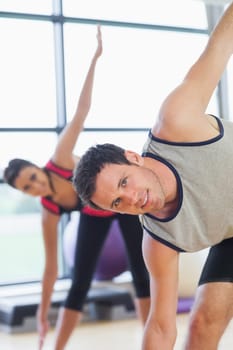 Portrait of two sporty people stretching hands at yoga class in fitness studio