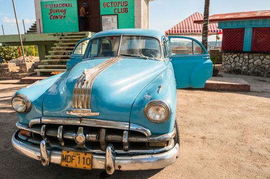 vintage car on pigs bay cuba with scubba diving center in background