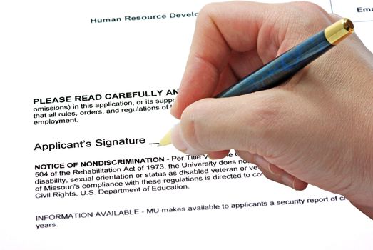 Hand with pen signing on a contract.