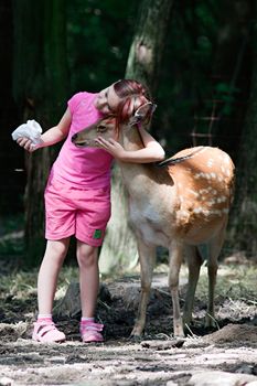 Photo of a young girl feeding sika deer and hugs him