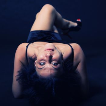 Woman lying on her back on a dark blurry background in blue illuminated