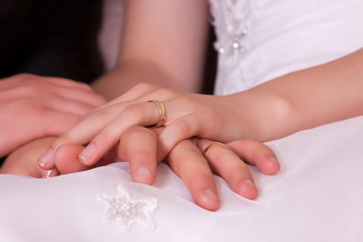 Photo crossed hands of newlyweds with wedding rings