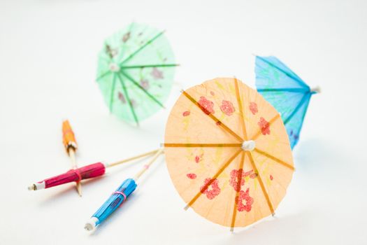 Different colors of cocktail umbrellas on a white background.