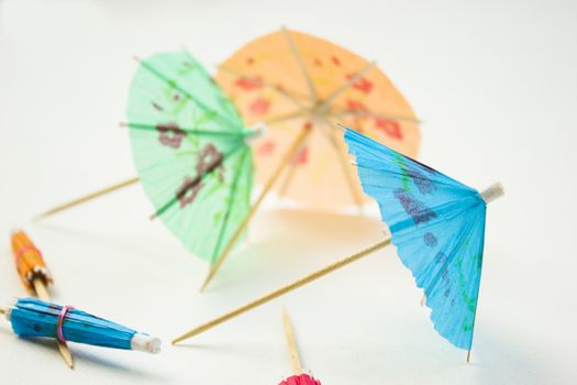 Different colors of cocktail umbrellas on a white background.