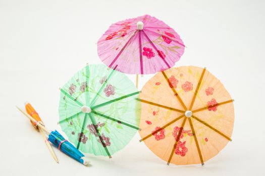 Different colors of cocktail umbrellas on a white background.