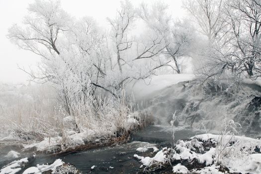 Frozen stream with waterfall and icicles in the winter, Ukraine. 