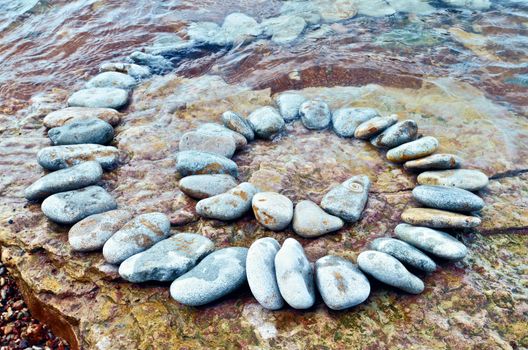 Spiral of white pebbles on the sea boulder