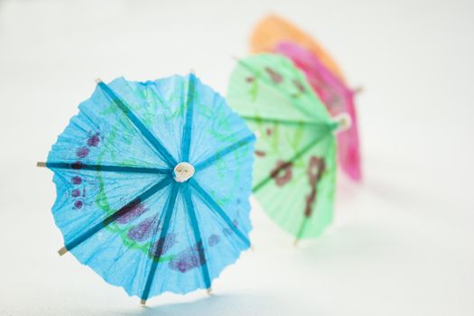 Different colors of cocktail umbrellas on a white background.