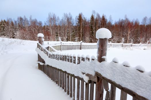 Winter landscape in the countryside. Old wooden fence. Lots of snow. 