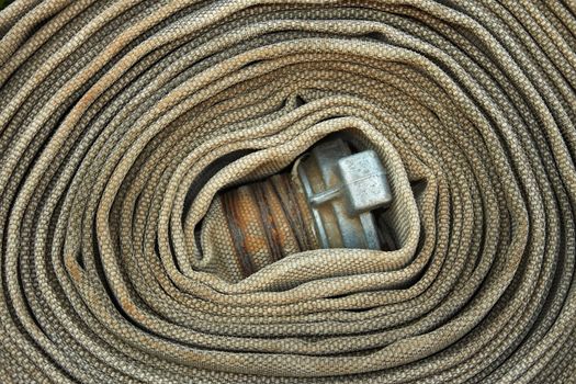 Old rolled fire hose with nozzle close-up