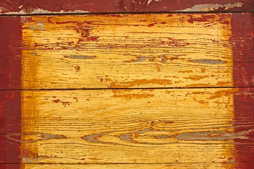 Detail the old shield of parallel horizontal wooden boards painted in yellow with red frame